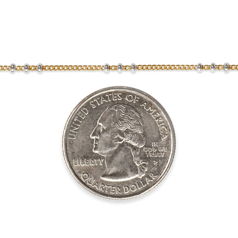Two tone chain next to a quarter dollar coin on a white background
