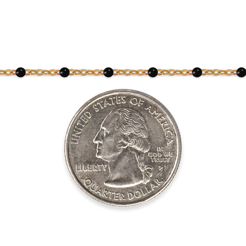 Gold chain with black beads and a quarter coin on a white background