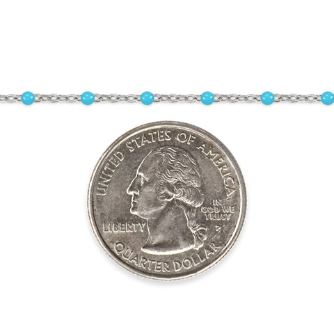 Silver chain with sky blue enamel beads and a quarter dollar coin on a white background