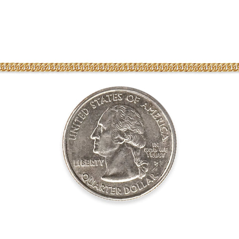 Gold-filled cuban chain next to a quarter dollar coin on a white background