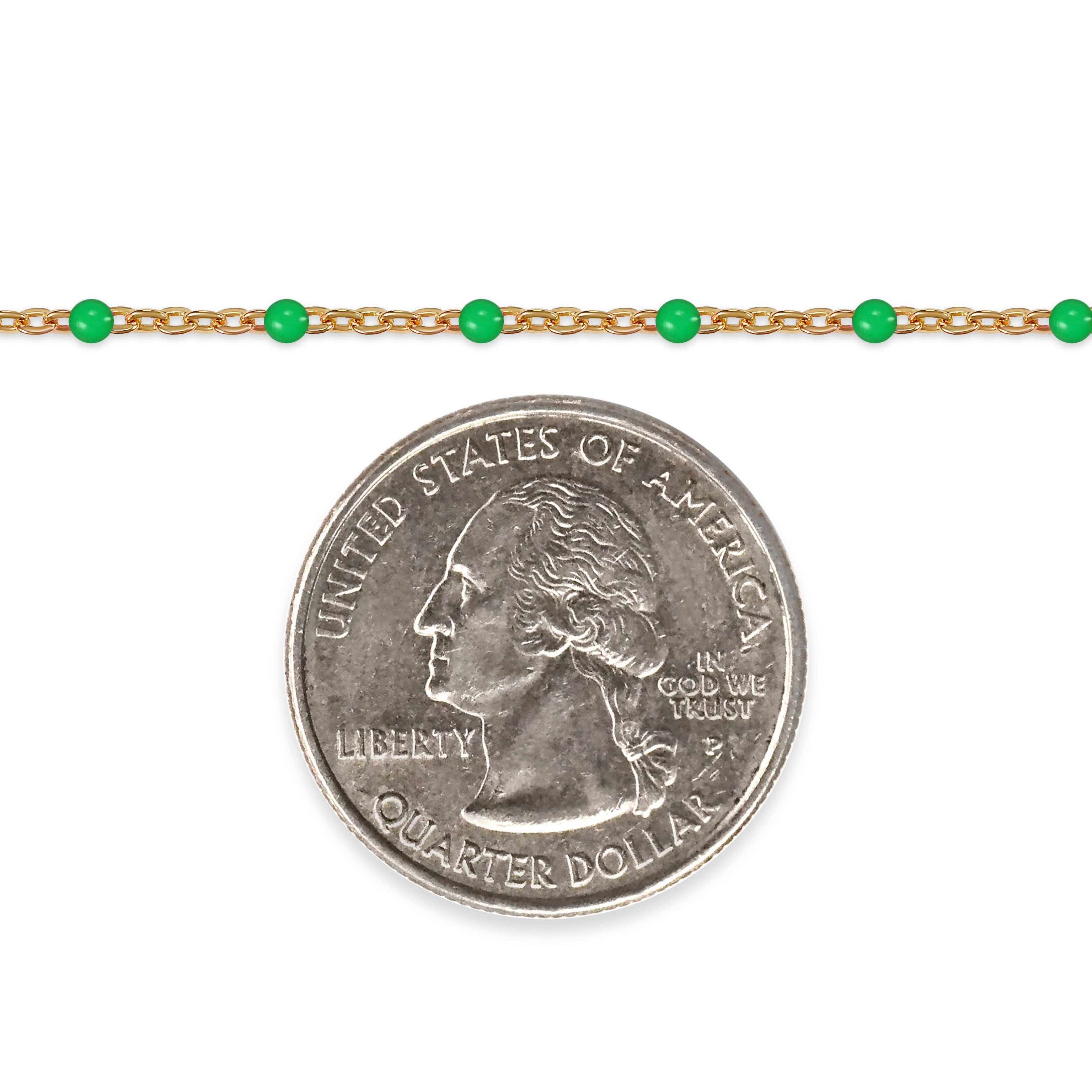 Gold chain with green beads next to a quarter on a white background