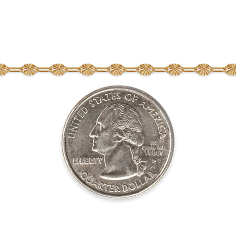 Gold chain next to a quarter dollar coin on a white background