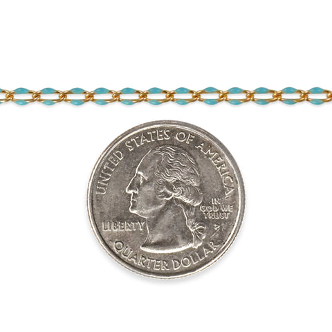 Gold filled chain with blue enamel next to a quarter dollar coin on a white background