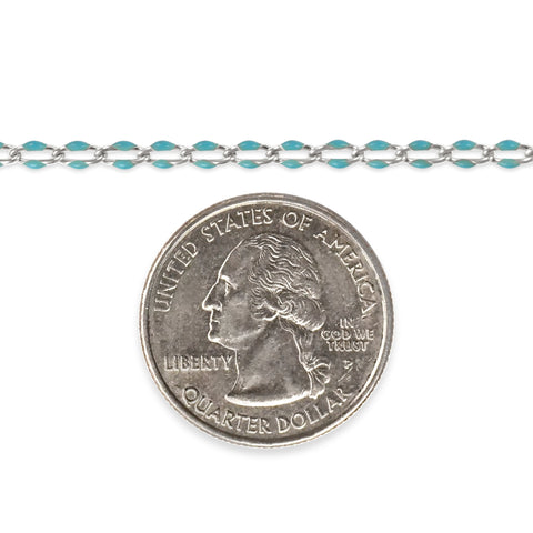 Silver chain with blue enamel next to a quarter on a white background