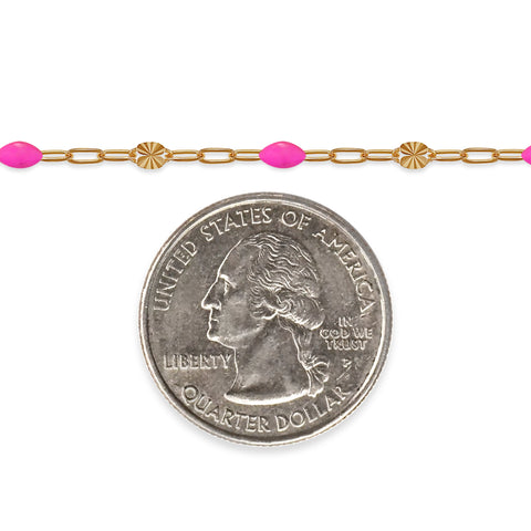 Gold chain with pink beads next to a quarter on a white background