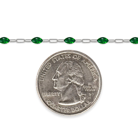 Silver chain with green enamel next to a quarter on a white background