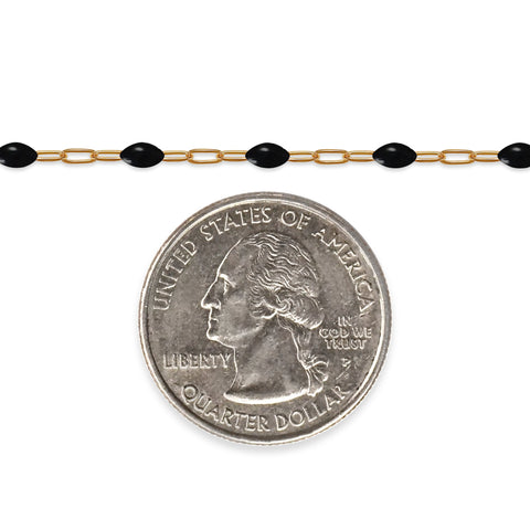 Gold filled chain with black enamel beads next to a quarter dollar coin on a white background