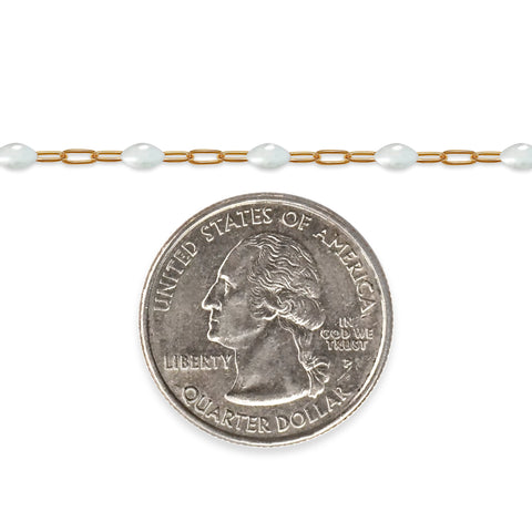 Gold filled chain with white enamel next to a quarter on a white background