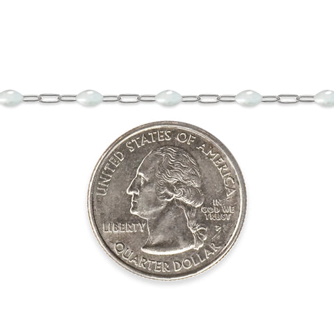 Silver chain with white enamel next to a quarter on a white background